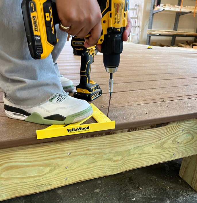 Glenn High School student securing fasteners on deck with YellaWood brand triangle square.